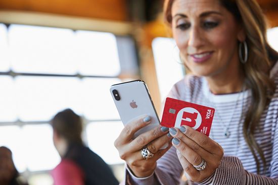 Woman holding UW Credit Union Card while looking at her phone Woman holding UW Credit Union Card while looking at her phone